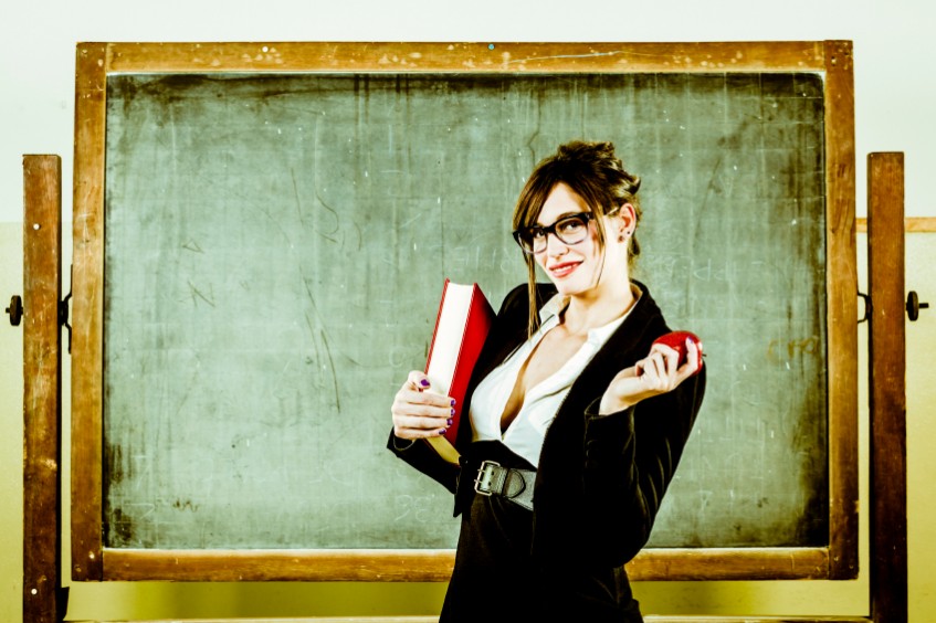 Woman in front of green blackboard, wearing sexy teacher gear