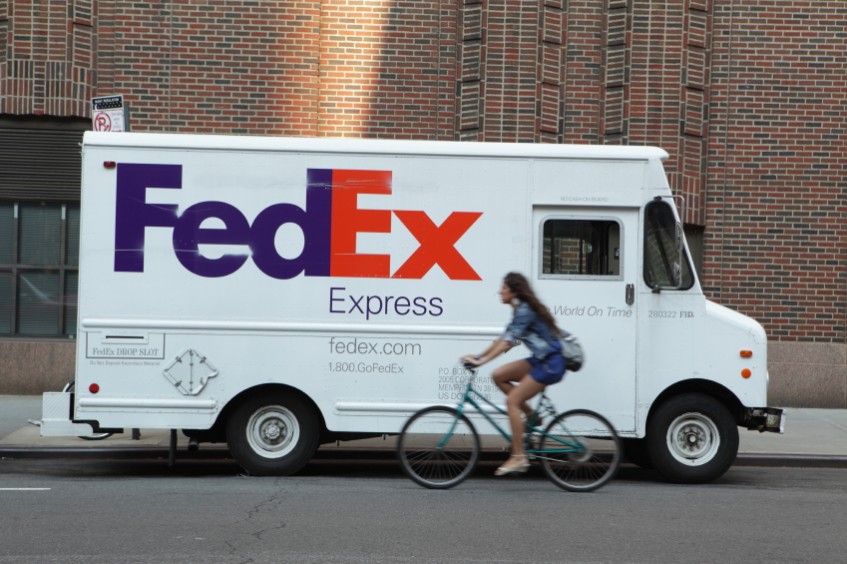 A Fed-Ex van with a bike riding past it