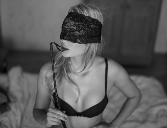 Sexy blonde woman with lace eye cover and whip black and white, bdsm